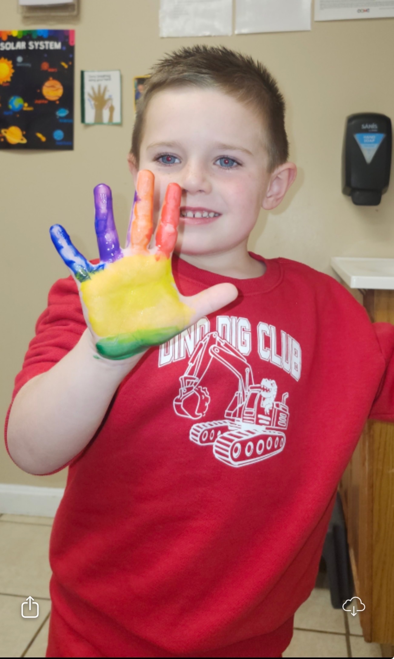 Child showing a colorful painted hand activity